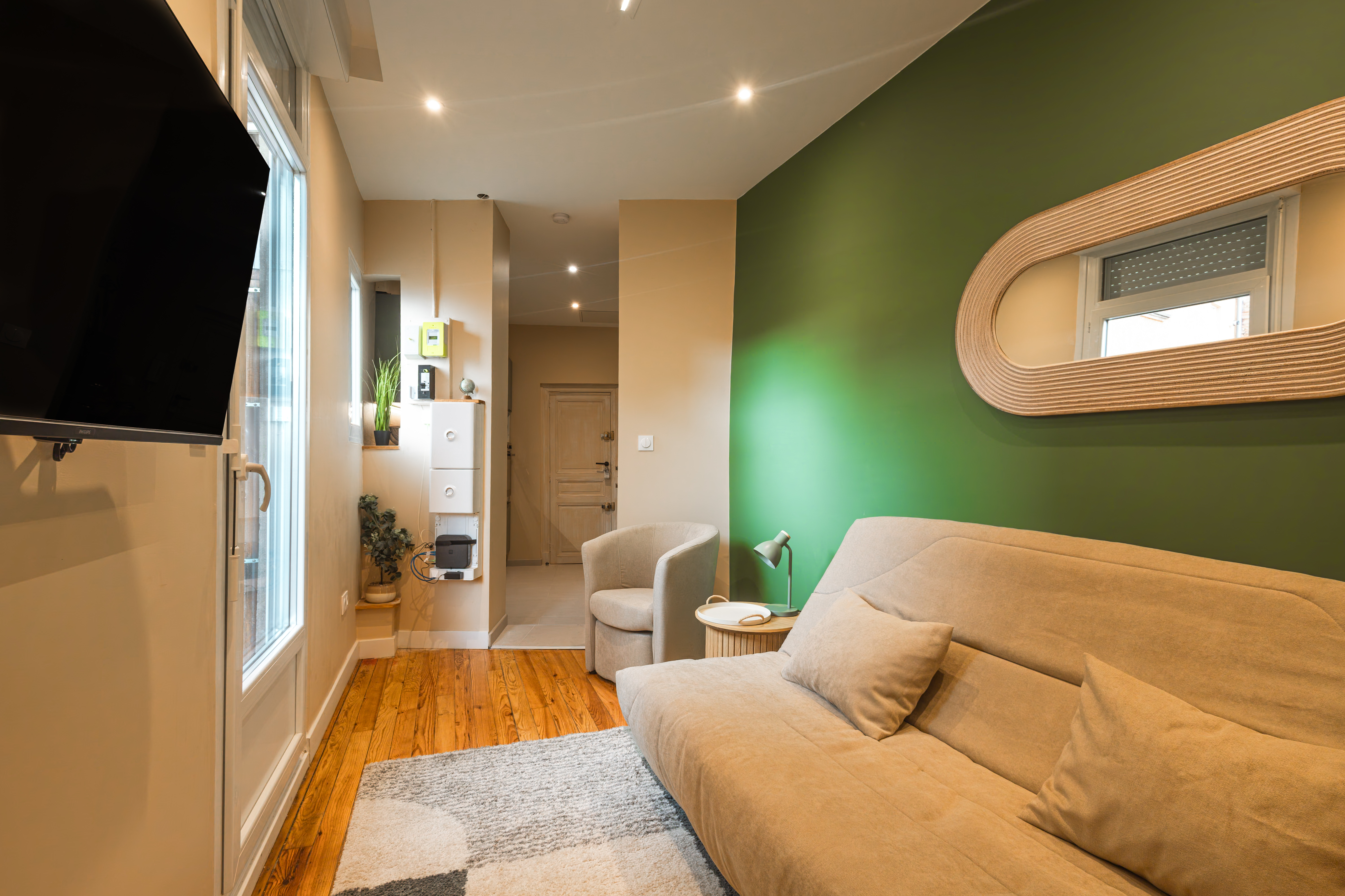 Salon : canapé lin, mur vert d'accent et miroir arche